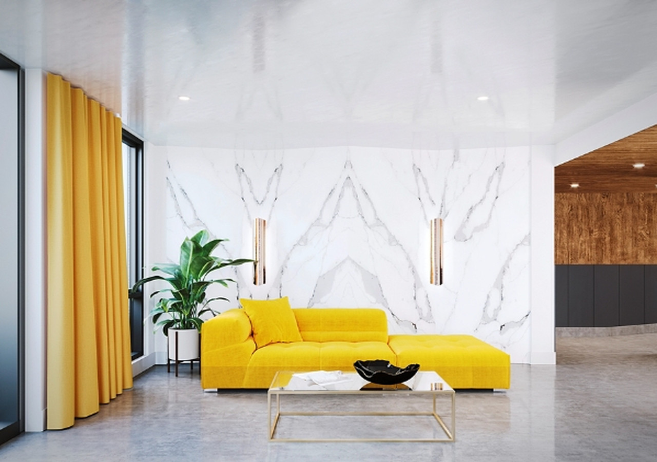 Hall d'entrée des appartements Wilcox avec un divan jaune et un mur de marbre